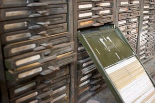 An old steel kardex, with one drawer pulled out, revealing a bunch of index cards. The margins of the cards are visible.