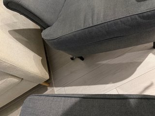A black and white corgi cardigan hiding behind a recliner chair.